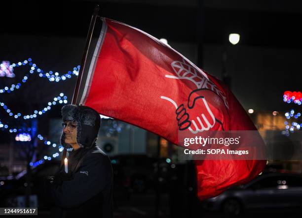 Man holds a candle and the Democratic Socialist of America flag at a Transgender Day of Remembrance Vigil. A crowd gathered at the Public Square for...