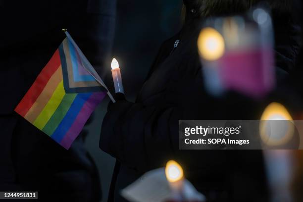 Woman holds a Pride flag as others hold candles during the vigil. A crowd gathered at the Public Square for a Transgender Day of Remembrance Sunday...
