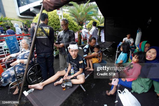 Wounded people rest under a tent displayed outside a hospital following an earthquake in Cianjur on November 21, 2022. - At least 56 people were...