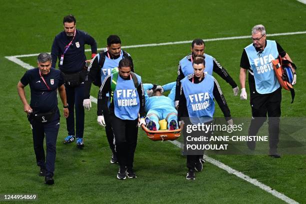 Iran's goalkeeper Alireza Beiranvand leaves the pitch on a stretcher after he was injured in a crash on heads with Iran's defender Majid Hosseini...