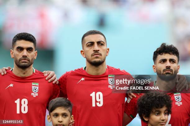 Iran's midfielder Ali Karimi, Iran's defender Majid Hosseini and Iran's defender Sadegh Moharrami listen to the national anthem ahead of the Qatar...