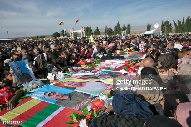 Relatives mourn over the caskets of 11 people killed in Turkish air strikes during their funeral in al-Malikiyah in Syria's northeastern Hasakah...