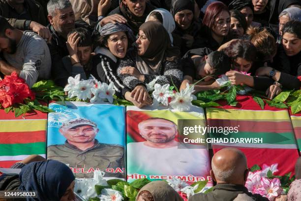 Relatives mourn over the caskets of 11 people killed in Turkish air strikes during their funeral in al-Malikiyah in Syria's northeastern Hasakah...