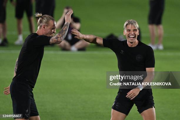 Denmark's defender Simon Kjaer laughs with Denmark's defender Jens Stryger Larsen as they take part in a training session at the al Sailiya SC...