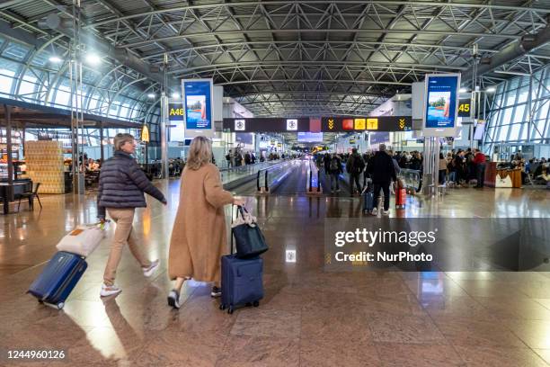 General view of the gates area in Brussels Airport with illuminated signs for the gates. Morning departing and arriving passengers are seen carrying...