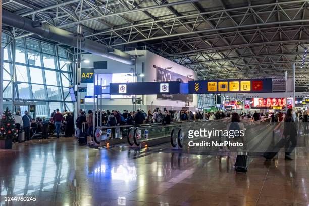 General view of the gates area in Brussels Airport with illuminated signs for the gates. Morning departing and arriving passengers are seen carrying...