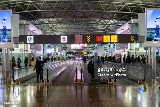General view of the gates area in Brussels Airport with illuminated signs for the gates. Morning departing and arriving passengers are seen carrying...