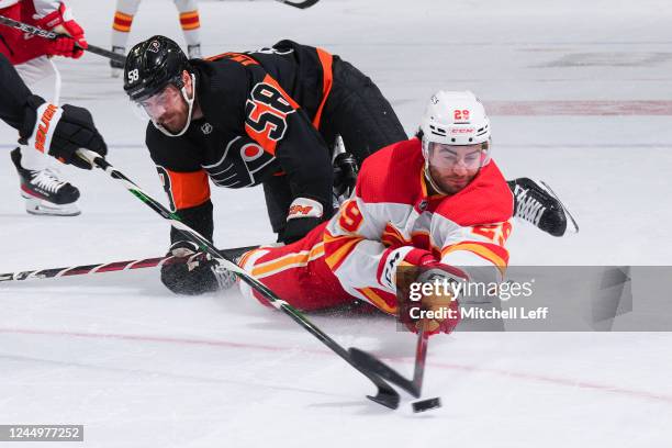 Dillon Dube of the Calgary Flames falls to the ice against Tanner Laczynski of the Philadelphia Flyers in the first period at the Wells Fargo Center...