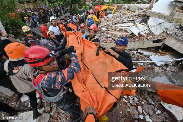 Rescue workers carry the body of a victim in Cianjur on November 22 following a 5.6-magnitude earthquake that killed at least 162 people, with...