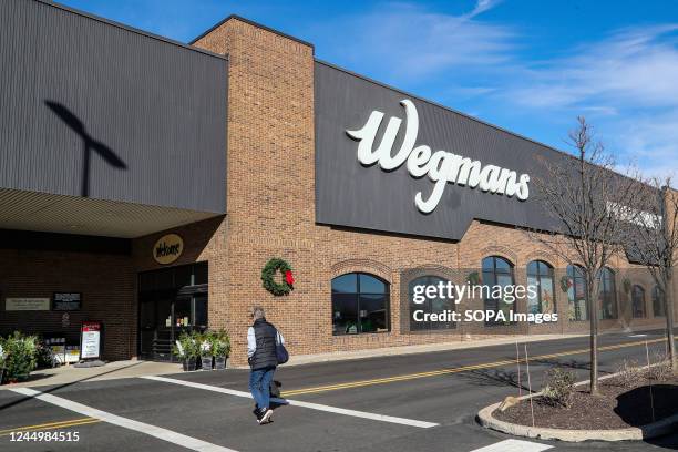 Woman is seen approaching the entrance of a Wegmans supermarket.