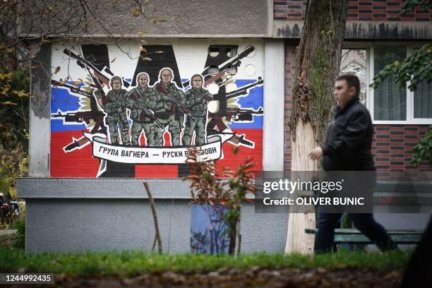 Pedestrian walks past a mural depicting Russia's para military mercenaries 'Wagner Group' reading : "Wagner Group - Russian knights" on a building's...