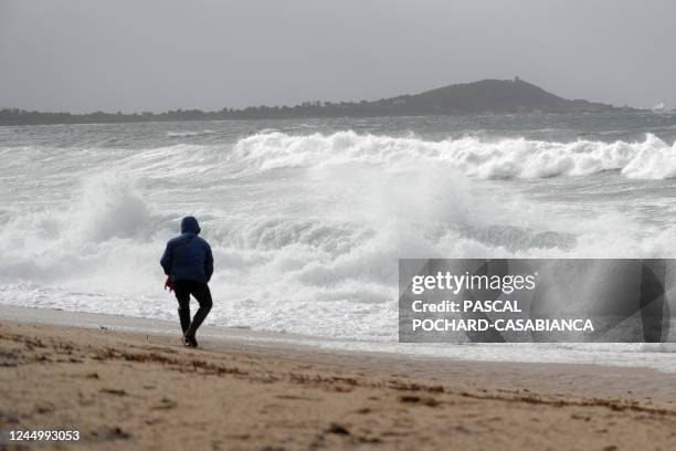 Man walks on the Agosta beach on November 22, 2022 in Albitreccia as storm Denise hits the French Mediterranean island of Corsica.