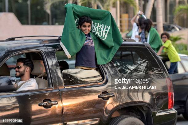 Young Saudi football fan waves their country's flag from a vehicle as they celebrate their win over Argentina in the Qatar 2022 World Cup, in the...