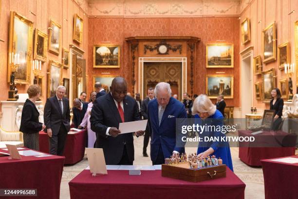 South Africa's President Cyril Ramaphosa along with Britain's King Charles III and Britain's Queen Consort Camilla look at a chess set, which was a...