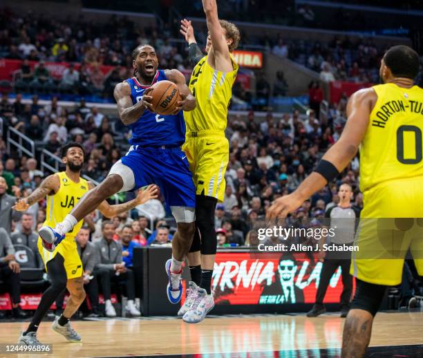 Los Angeles, CA Clippers forward Kawhi Leonard, center, drives to the hoop under pressure from Utah Jazz forward Lauri Markkanen, in the second half...