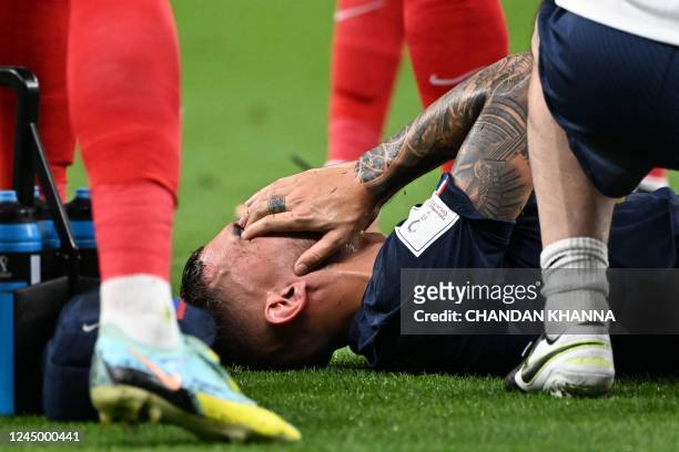 France's defender Lucas Hernandez reacts after he sustained an injury during the Qatar 2022 World Cup Group D football match between France and...