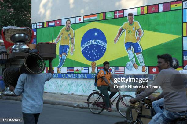 People walk past wall graffiti of Brazilian football players Neymar and Vinicius Jr. To celebrate Qatar World Cup 2022 at Gopalnagar on November 22,...