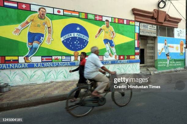 People walk past wall graffiti of Brazilian football players Neymar and Vinicius Jr. To celebrate Qatar World Cup 2022 at Gopalnagar on November 22,...