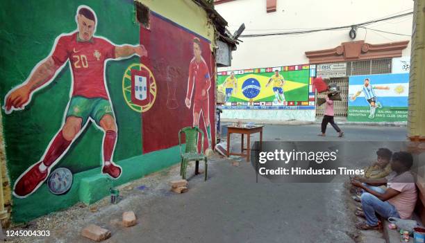 People walk past wall graffiti of football players Ronaldo, Neymar, Vinicius Jr. And Messi to celebrate Qatar World Cup 2022 at Gopalnagar on...