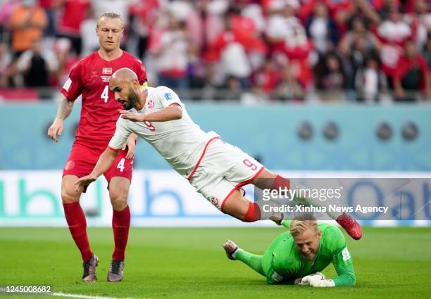 Issam Jebali C of Tunisia vies with Simon Kjaer L and Kasper Schmeichel of Denmark during the Group D match between Denmark and Tunisia at the 2022...