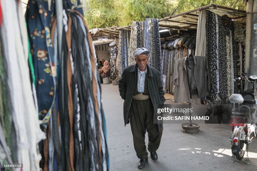 Iraq Textile A Kurdish man in a traditional outfit walks past textile shops in a ...