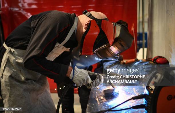 France's Junior Minister for Industry Roland Lescure , next to a student, uses a welding torch during his visit to the "Iron Academy" production...