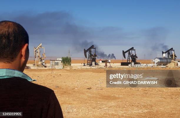 This picture shows pumpjacks in an oil field and smoke plumes rising in the background, following reported Turkish drone strikes near the town of...