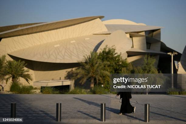 Woman walks past the National Museum of Qatar in Doha on November 23, 2022 during the Qatar 2022 World Cup football tournament.