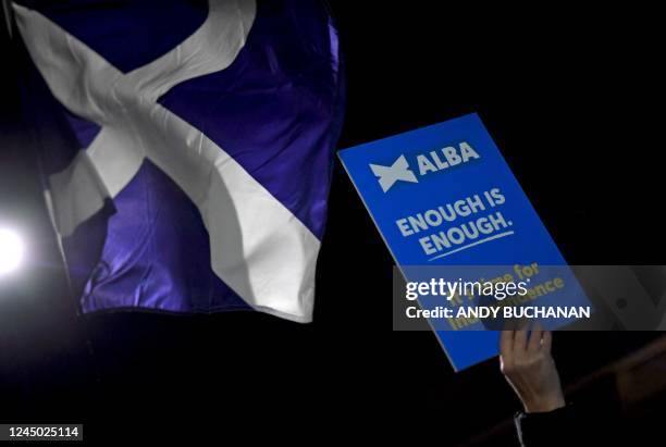Pro-Scottish independence supporter holds an ALBA party placard alongside calling for a Referendum, alongside a Saltire flag, during a rally outside...
