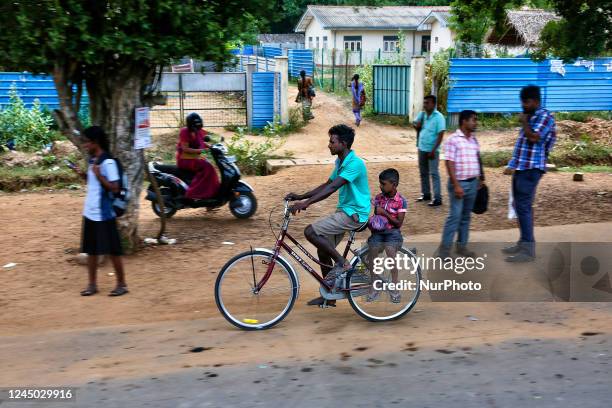Boy rides on the back of a bicycle in Kilinochchi, Sri Lanka.