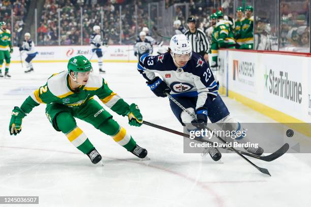 Michael Eyssimont of the Winnipeg Jets and Calen Addison of the Minnesota Wild compete for the puck in the first period of the game at Xcel Energy...