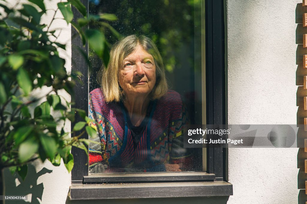 Senior lady looking through window