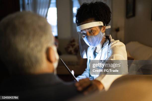 female doctor visiting her patient at his home - appointment with digital tablet - brazil covid stock pictures, royalty-free photos & images