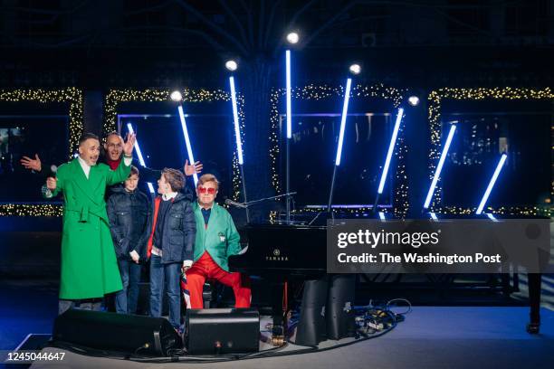 Elton John is joined by his children, husband David Furnish, left, and Saks Fifth Avenue CEO Marc Metrick at an event to unveil the 2022 holiday...