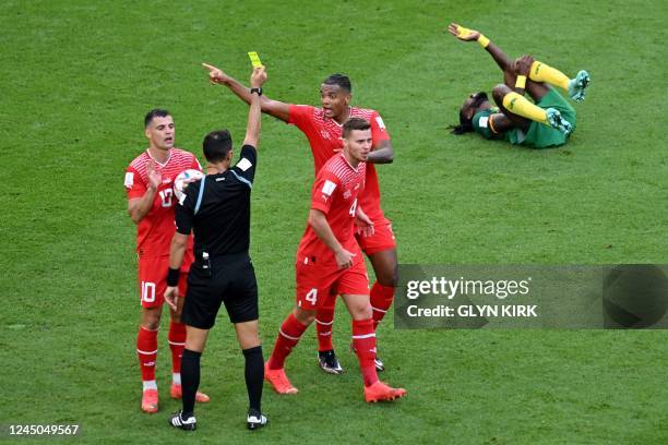 Switzerland's defender Manuel Akanji receives a yellow card from Argentinian referee Facundo Tello as Cameroon's midfielder Andre-Frank Zambo...