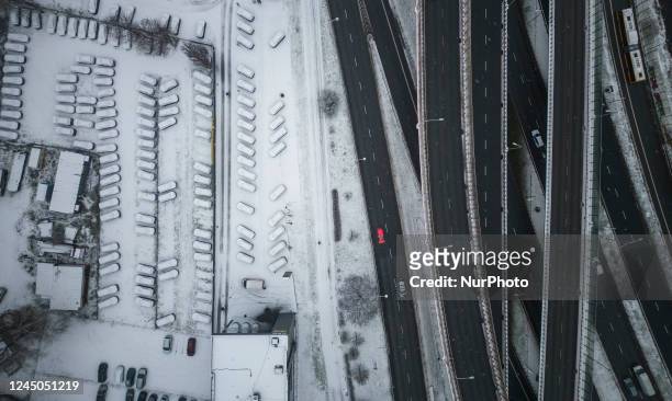Cars covered in snow parked at a car dealership are seen next to a highway in Warsaw, Poland on 24 November, 2022.