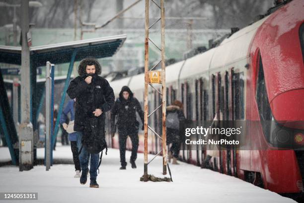 Man zips up his jacket during snowfall at a train station in Warsaw, Poland on 24 November, 2022.