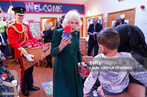 Britain's Camilla, Queen Consort gives out a Paddington bear teddy during a visit to Barnardo's Nursery in Bow, east London on November 24, 2022....