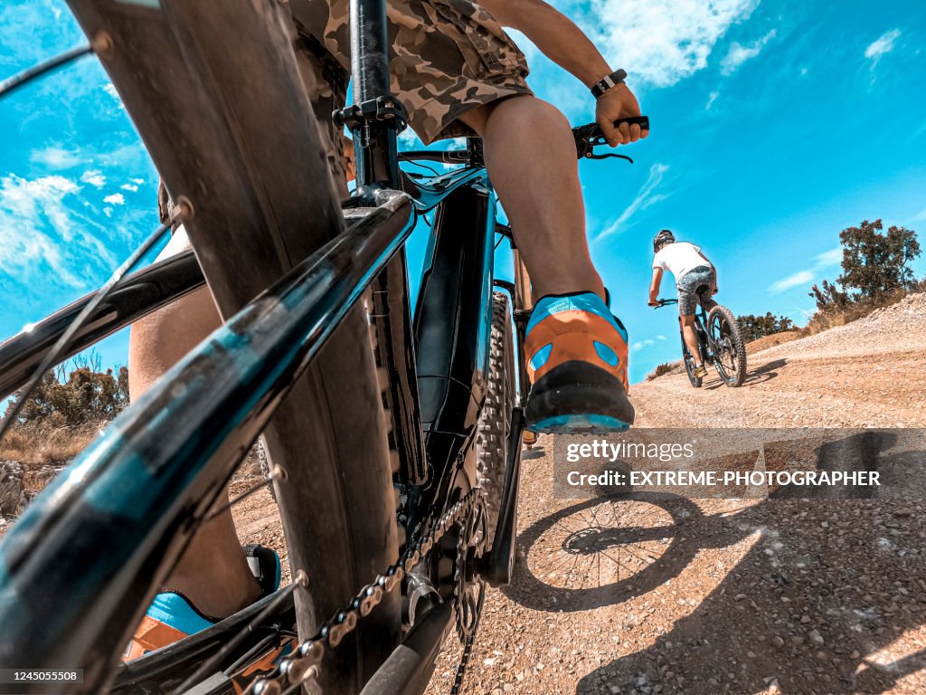 An action point of view of a cycler riding an e-bike in a race across the country side on a sunny day