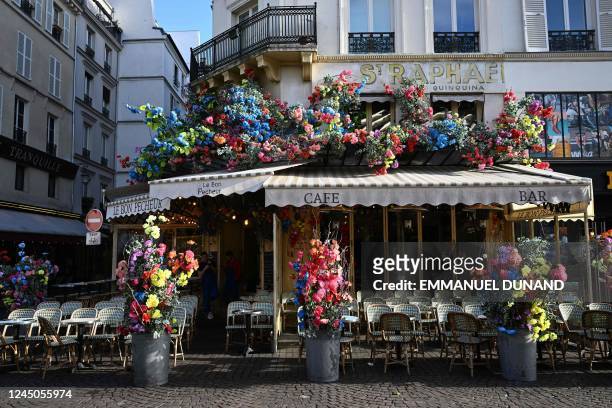 This photograph taken on November 24, 2022 shows the facade of a cafe decorated with artificial flowers in Paris. - Since a few years, the facades of...