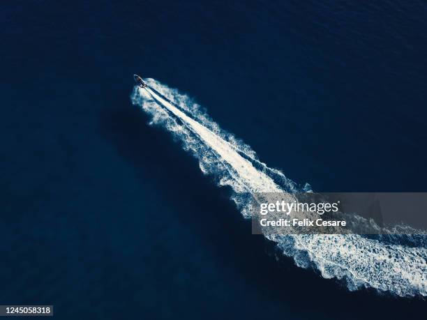 aerial view of a jetski boat swirling in a deep blue waters. boat wake from above. - jet boat fotografías e imágenes de stock