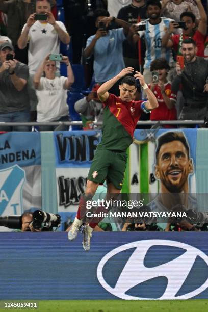 Portugal's forward Cristiano Ronaldo celebrates after scoring his team's first goal from the penalty spot as a banner depicting Argentine forward...