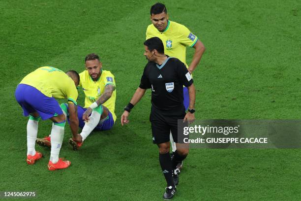 Iranian referee Alireza Faghani looks at Brazil's forward Neymar as he sits on the ground during the Qatar 2022 World Cup Group G football match...