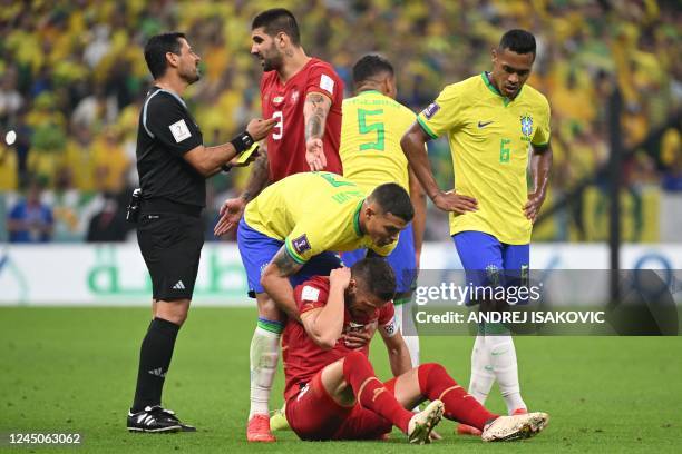 Serbia's forward Dusan Tadic is tended to by Brazil's defender Thiago Silva as Serbia's defender Strahinja Erakovic speaks with Iranian referee...