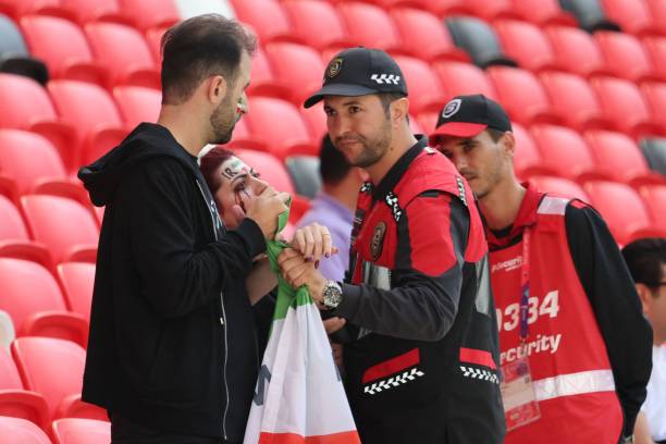 Members of security speak with two Iran supporters, as they take away a flag reading "Woman life freedom", prior to the Qatar 2022 World Cup Group B...