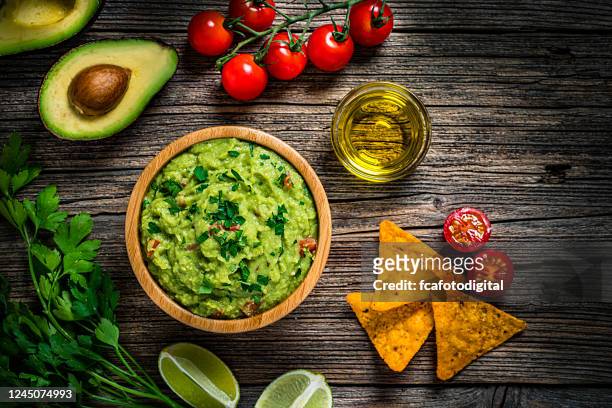 guacamole and chips on rustic wooden table - guacamole stock pictures, royalty-free photos & images