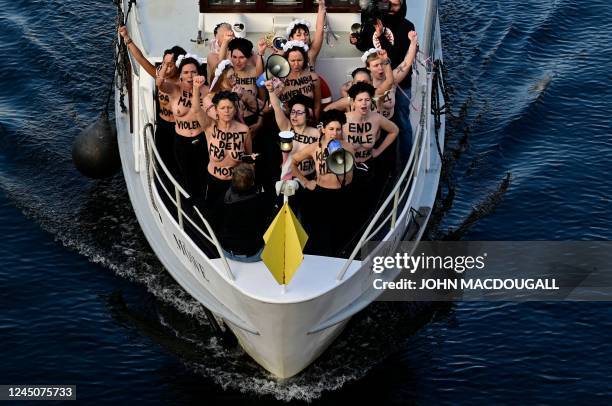 Activists of feminist activist group Femen shout slogans while standing on a boat on the Spree river during a protest action on the International Day...