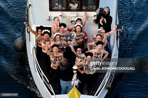 Activists of feminist activist group Femen shout slogans while standing on a boat on the Spree river during a protest action on the International Day...