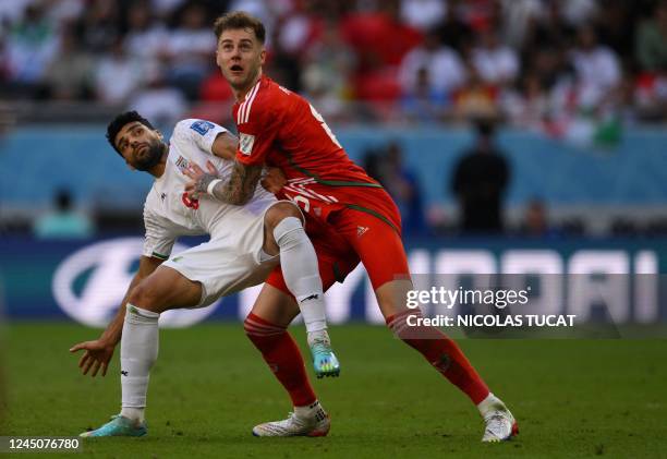 Iran's forward Mehdi Taremi and Wales' defender Joe Rodon fight for the ball during the Qatar 2022 World Cup Group B football match between Wales and...