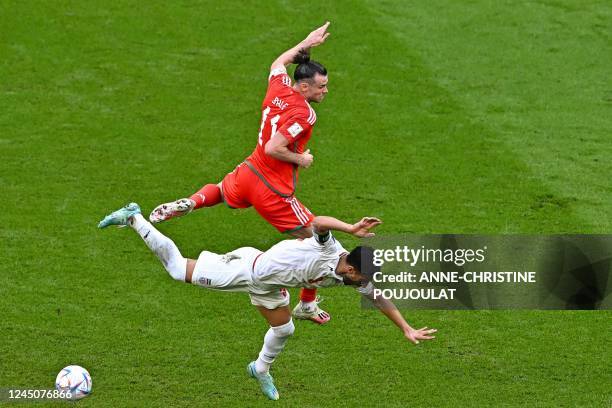 Iran's defender Ehsan Hajsafi fights for the ball with Wales' forward Gareth Bale during the Qatar 2022 World Cup Group B football match between...